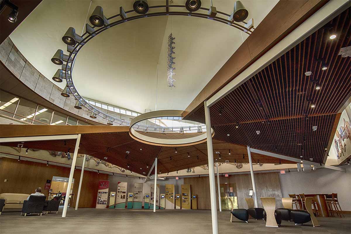 The library space below, housing casual seating and small exhbitions, opens above to the soaring expanse of the rotunda, featuring a large ring of lights and a model DNA strand hanging in the center.